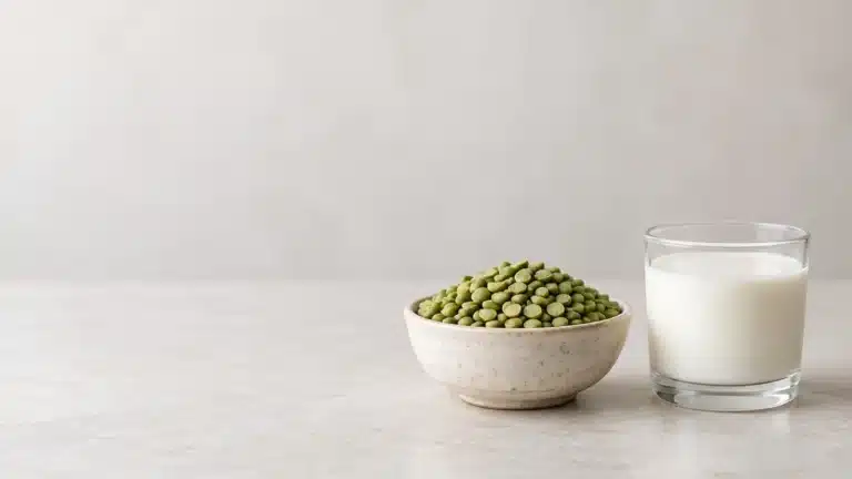 Cuenco de chícharos secos junto a un vaso de leche sobre superficie clara